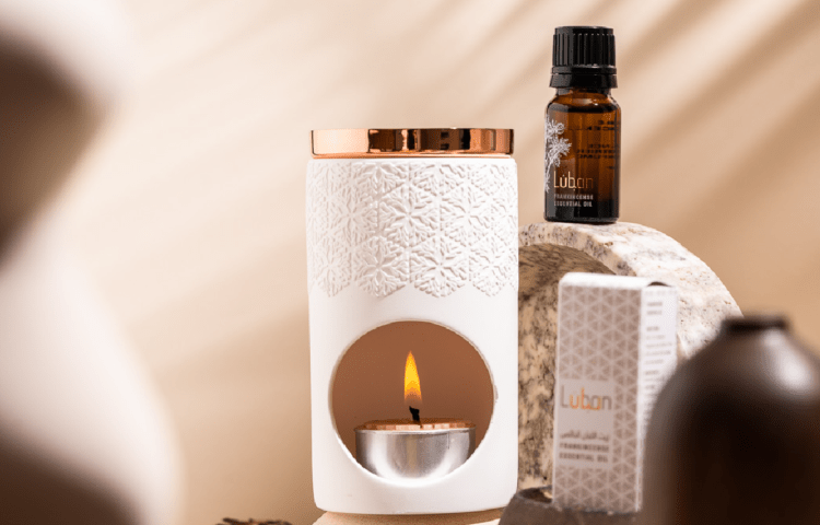 Frankincense essential oil and a lit candle in a cylindrical packaged box