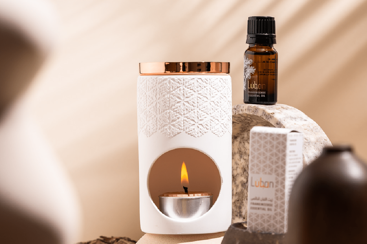 Frankincense essential oil and a lit candle in a cylindrical packaged marterial